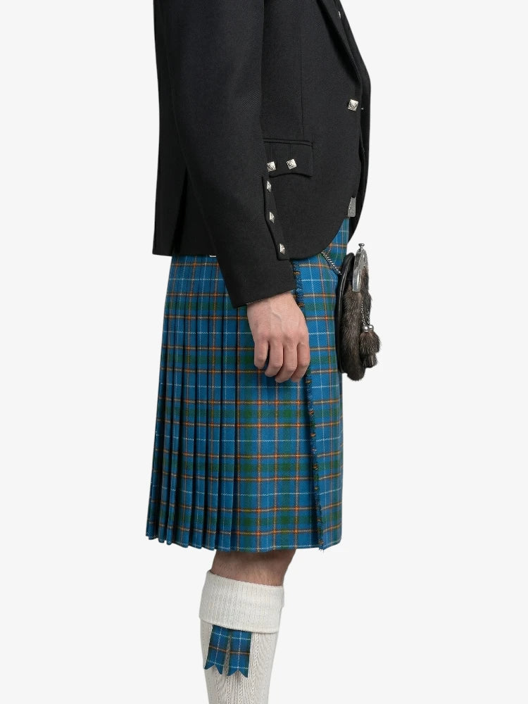 Person wearing a black jacket and blue plaid kilt on a white background