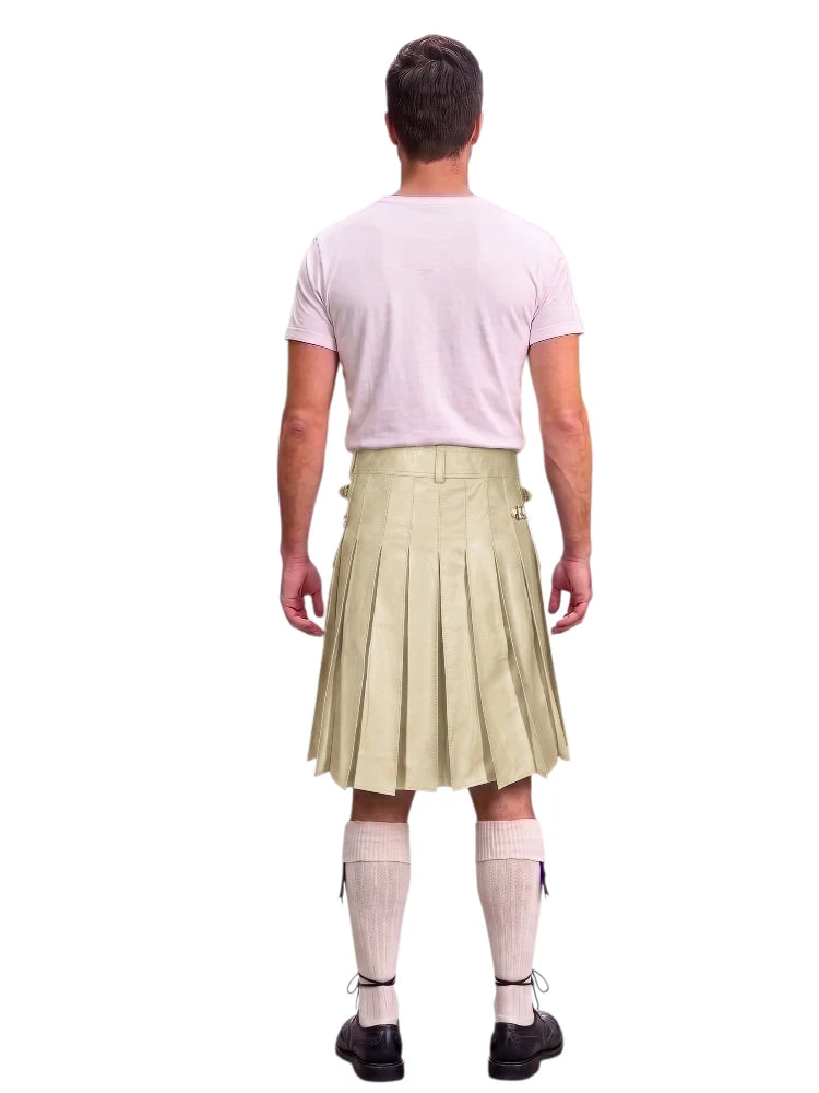 A man shown from the back wearing a light beige pleated kilt, a pale pink t-shirt, white knee-high socks, and black shoes, isolated on a white background.