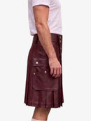 A side view of a person wearing a dark burgundy faux-leather kilt with silver snap buttons and flap pockets, paired with a white t-shirt, against a plain white background.