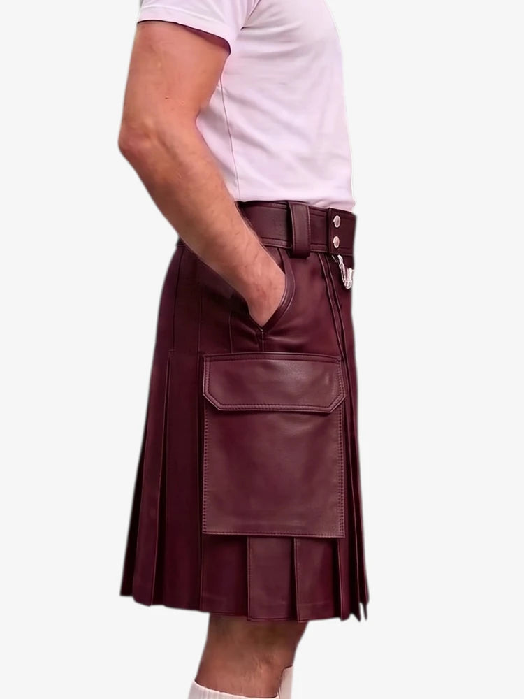 A dark green faux-leather kilt with pleated detailing, a front flap pocket, and a belt with silver-tone buttons, shown on a model wearing a light pink t-shirt against a white background.