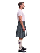 A man shown in profile wearing a dark gray leather kilt, a white t-shirt, white knee-high socks with a purple accent, and black leather shoes, against a plain white background.