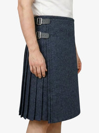 Person wearing a navy pleated skirt with a white background