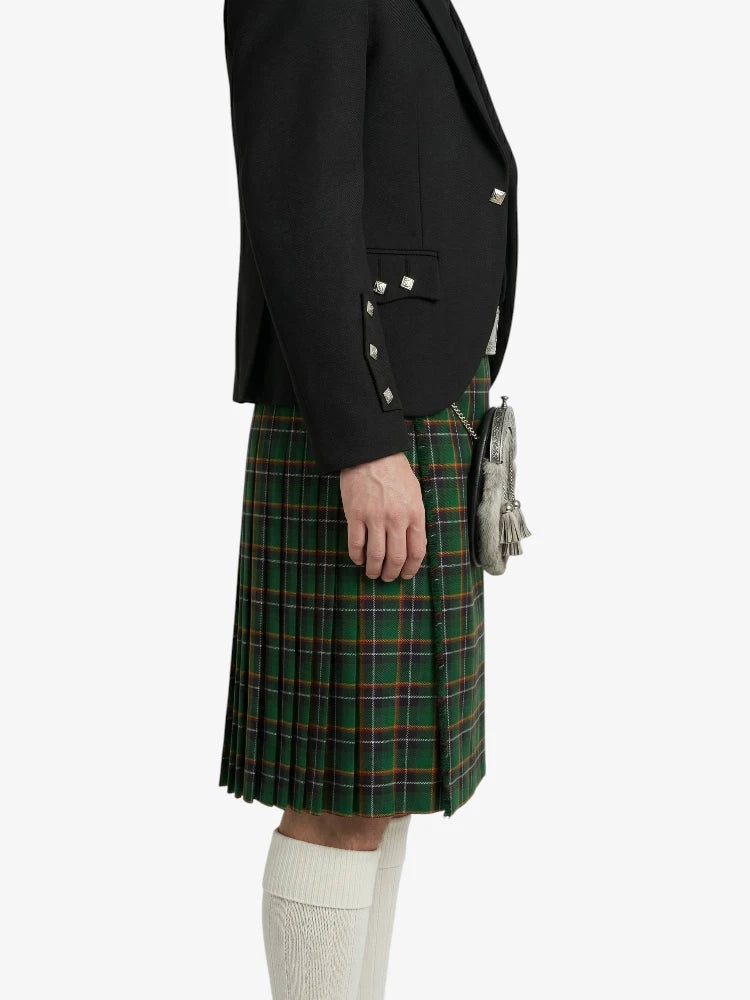 Person wearing a black blazer and green plaid kilt on a white background