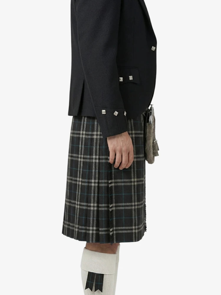 Person wearing a black jacket and plaid kilt on a white background