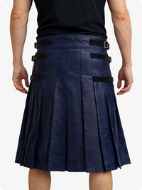 Person wearing a navy pleated kilt with black straps on a white background