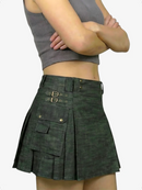 Person wearing a green pleated skirt with a gray top on a white background